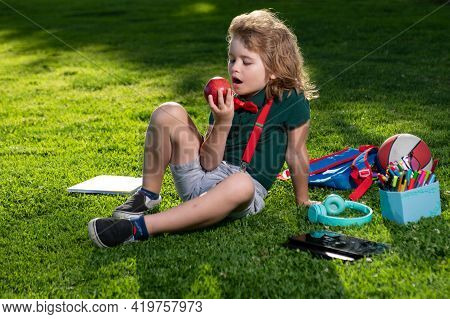 Kid Sitting Outdoor In Garden Eating Apple. Lttle Child Outdoor School, Education, On Line Distance 