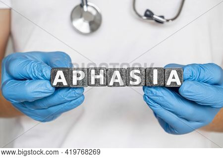 Aphasia - Word From Stone Blocks With Letters Holding By A Doctor's Hands In Medical Protective Glov