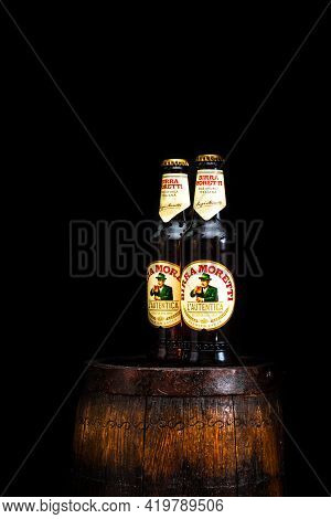 Bottle Of Birra Moretti Beer On Wooden Barrel With Dark Background. Illustrative Editorial Photo Buc
