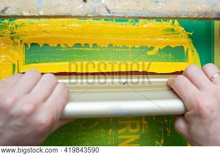 Serigraphy Silk Screen Print Process At Clothes Factory. Frame, Squeegee And Plastisol Color Paints.