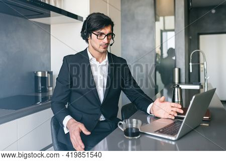 Businessman With Headset At A Video Conference From His Home Computer
