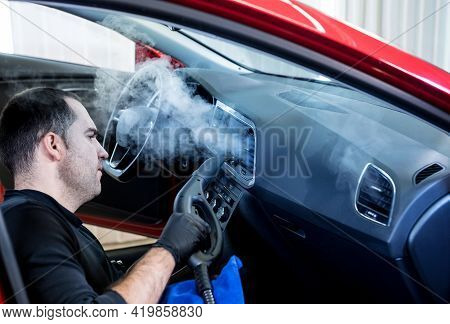 Car Service Worker Cleans Interiror With Steam Cleaner