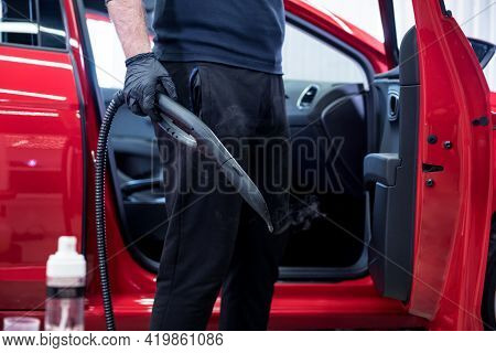 Car Service Worker Cleans Interiror With Steam Cleaner