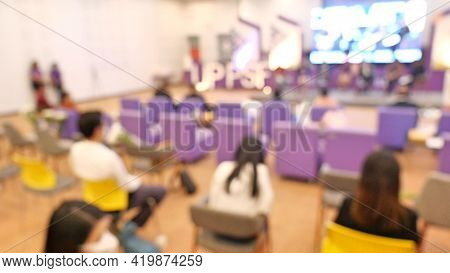 Blurred Image Of People Sit In Hall For Seminar. Arrange Social Distancing Seat For Reduce Infection