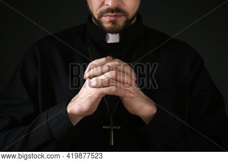 Priest In Cassock Praying On Dark Background, Closeup