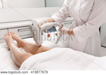 Close Up Of Laser Leg Hair Removal, Beautician At Spa Beauty Clinic Using Hardware Cosmetology Devic