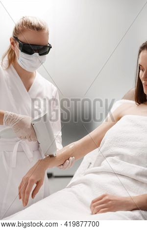 Beauty Clinic And Spa Concept. Beautician Cosmetologist In Glasses Using Laser, Remove Hair On Hand 