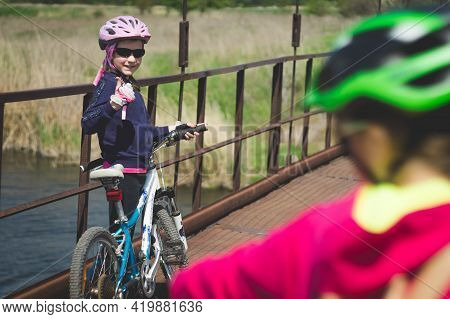 Konstantinovka, Ukraine - May 8, 2021: Little Girl In Helmet With Bicycle Shows Thumbs Up On The Old