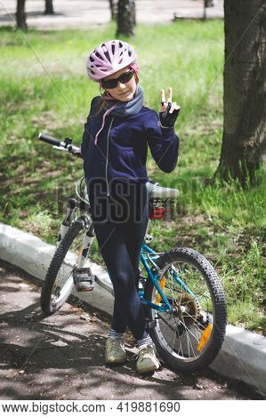 Konstantinovka, Ukraine - May 8, 2021: Little Girl Near The Bicycle Shows The Sign 