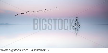Birds Flying Over A Cardinal Sailing Marker At Sunset On The Loughor Estuary, Llanelli, South Wales,