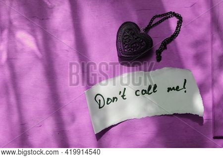 Handwritten Note Don't Call Me In A White Piece Of Paper And A Wooden Amulet In The Shape Of A Heart