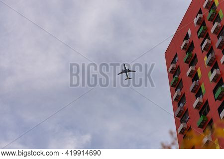 The Plane Flies Over The House. Against The Background Of A Cloudy Sky, We Can See The Edge Of The H