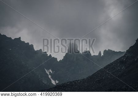 Dark Atmospheric Mountain Landscape With Black Pointy Rocky Peak In Gray Cloudy Sky. Lead Gray Low C