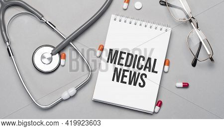 In The Notebook Is The Text Medical News, Next To A Stethoscope, Pills And Glasses.