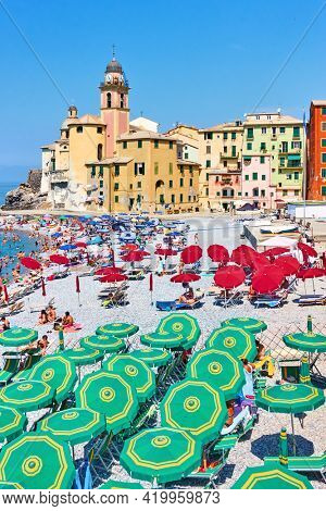 Camogli, Genoa, Italy - July 3, 2019:  Beach with parasols and sunbathing people in Camogli, Genova