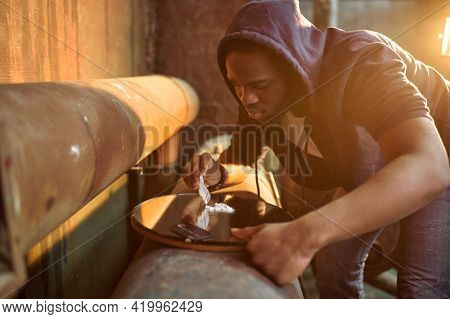Drug addict man prepares dose of powder, hellhole