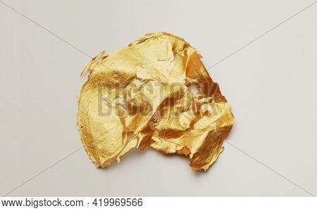 Gold glitter and bronze color blot. Abstract torn piece of metal leaf (potal) paper on white background. 