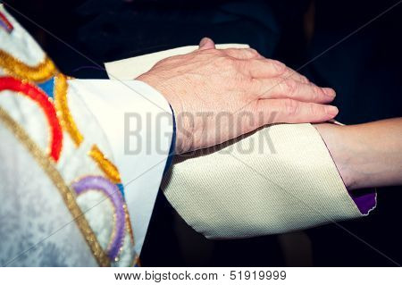 Catholic Priest Holding His Hand On Newlyweds' Hands Coverred In Stole