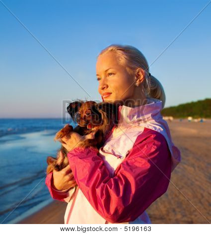 Ung kvinde med hendes hund på en strand