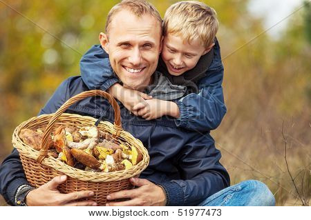 Father and son are happy that they have found a basket full of mushrooms