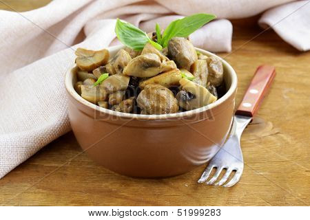 mushroom ragout of champignons and basil on a wooden table