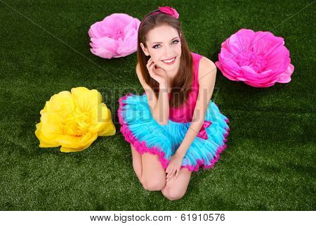 Beautiful young woman in petty skirt with flowers on grass