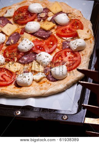 Raw pizza dough with mozzarella and proscuitto on top