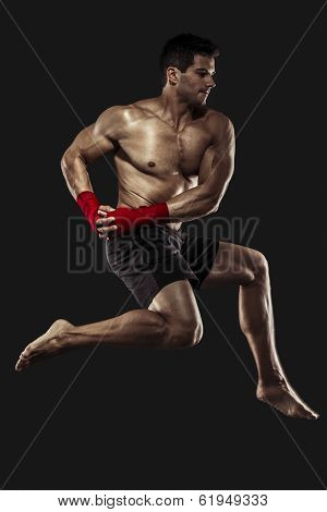 Portrait of a muscular man practicing body combat against a dark background