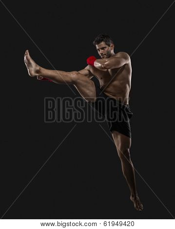 Portrait of a muscular man practicing body combat against a dark background