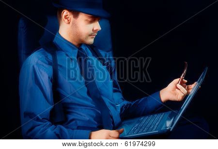 Man with Hat and Pipe Looking at Laptop