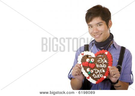 Mladý šťastný muž, který držel Oktoberfestu gingebread srdce