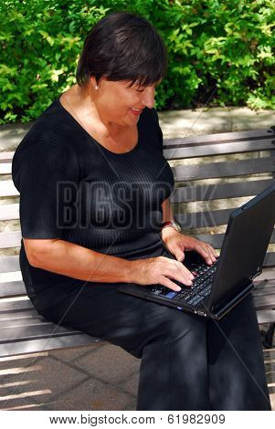 Mature woman typing on portable computer outdoor