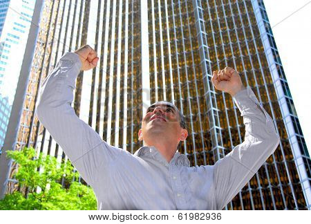 Triumphant businessman in the city raising arms in victory