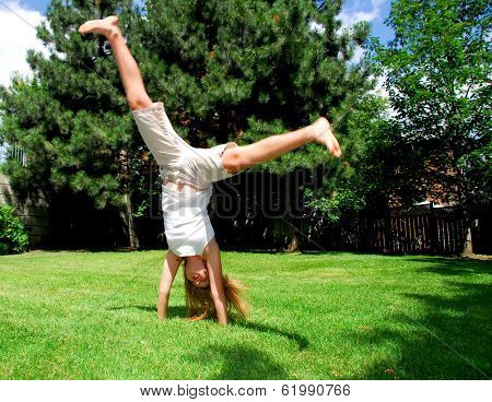Young girl doing a cartwheel on green grass