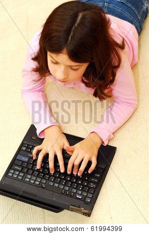 Young girl lying on the floor with portable computer