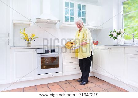 Happy Grandmother Baking A Pie In A White Kitchen