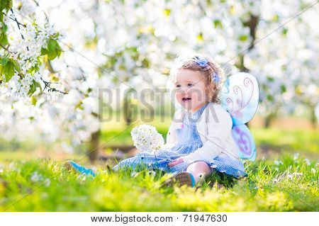 Curly Toddler Girl In Fairy Costume Playing In Fruit Garden