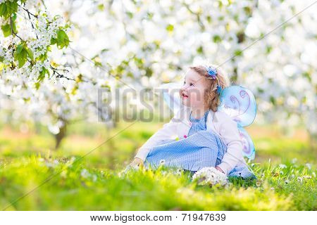 Curly Toddler Girl In Fairy Costume Playing In Fruit Garden