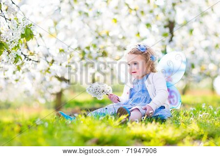 Curly Toddler Girl In Fairy Costume Playing In Fruit Garden