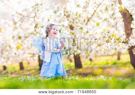 Curly Toddler Girl In Fairy Costume Playing In Fruit Garden