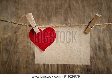 Red Fabric Heart With Sheet Of Paper Hanging On The Clothesline. On Old Wood Background.