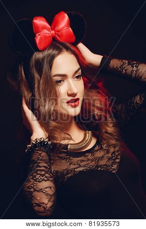Portrait of a beautiful model with a red bow on a dark background.
