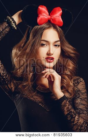 Portrait of a beautiful model with a red bow on a dark background.