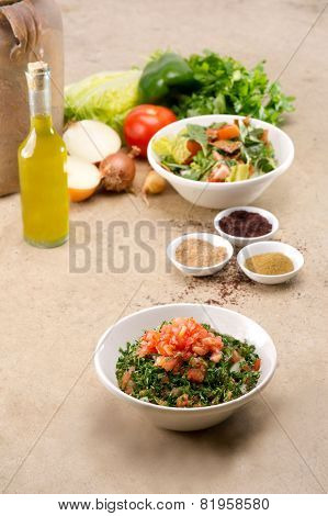 Plates of traditional Arabic salad fattouch and tabbouleh on a rustic background