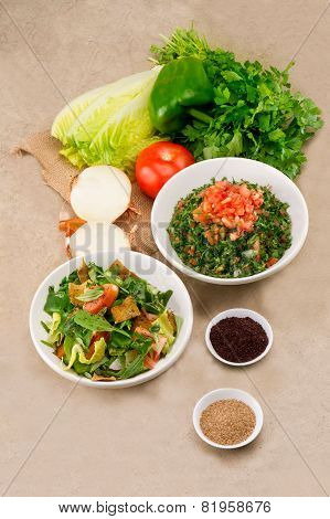 Plates of traditional Arabic salad fattouch and tabbouleh on a rustic background