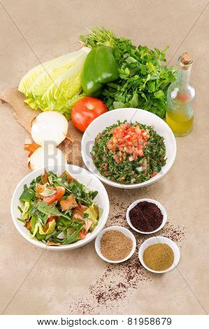 Plates of traditional Arabic salad fattouch and tabbouleh on a rustic background