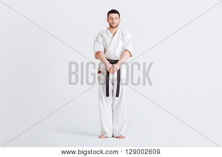 Full length portrait of a male fighter in kimono standing isolated on a white background