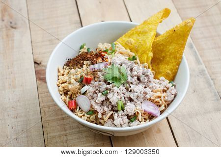 Spicy instant noodle with minced pork on wood background