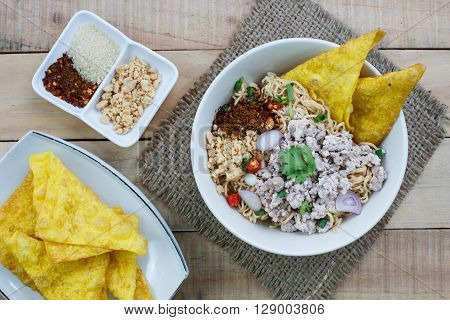 Spicy instant noodle with minced pork on wood background.Top view