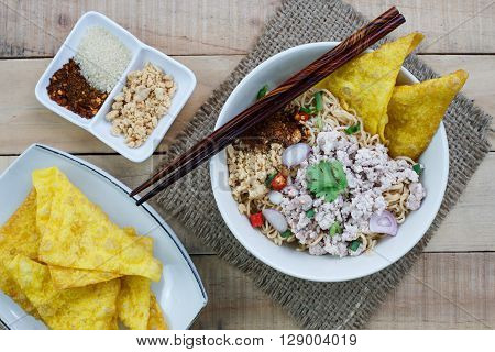 Spicy instant noodle with minced pork on wood background.Topview